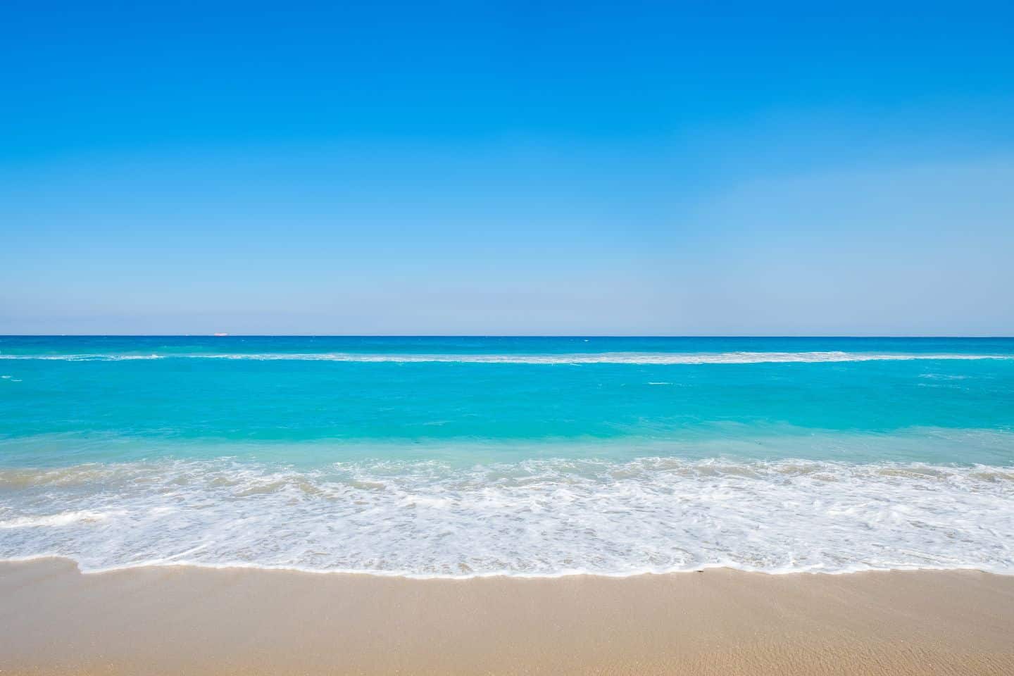 Turquoise water on tan sandy beach in Palm Beach, Florida