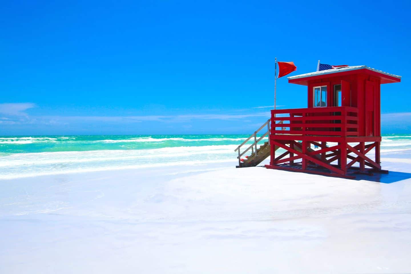 Blue sky with white sandy beaches with a red lifeguard tower